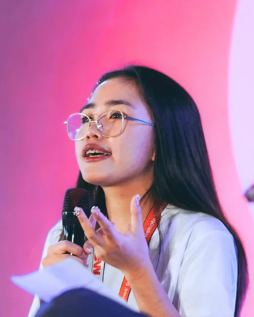 Joanna Ramos speaking on stage with a microphone